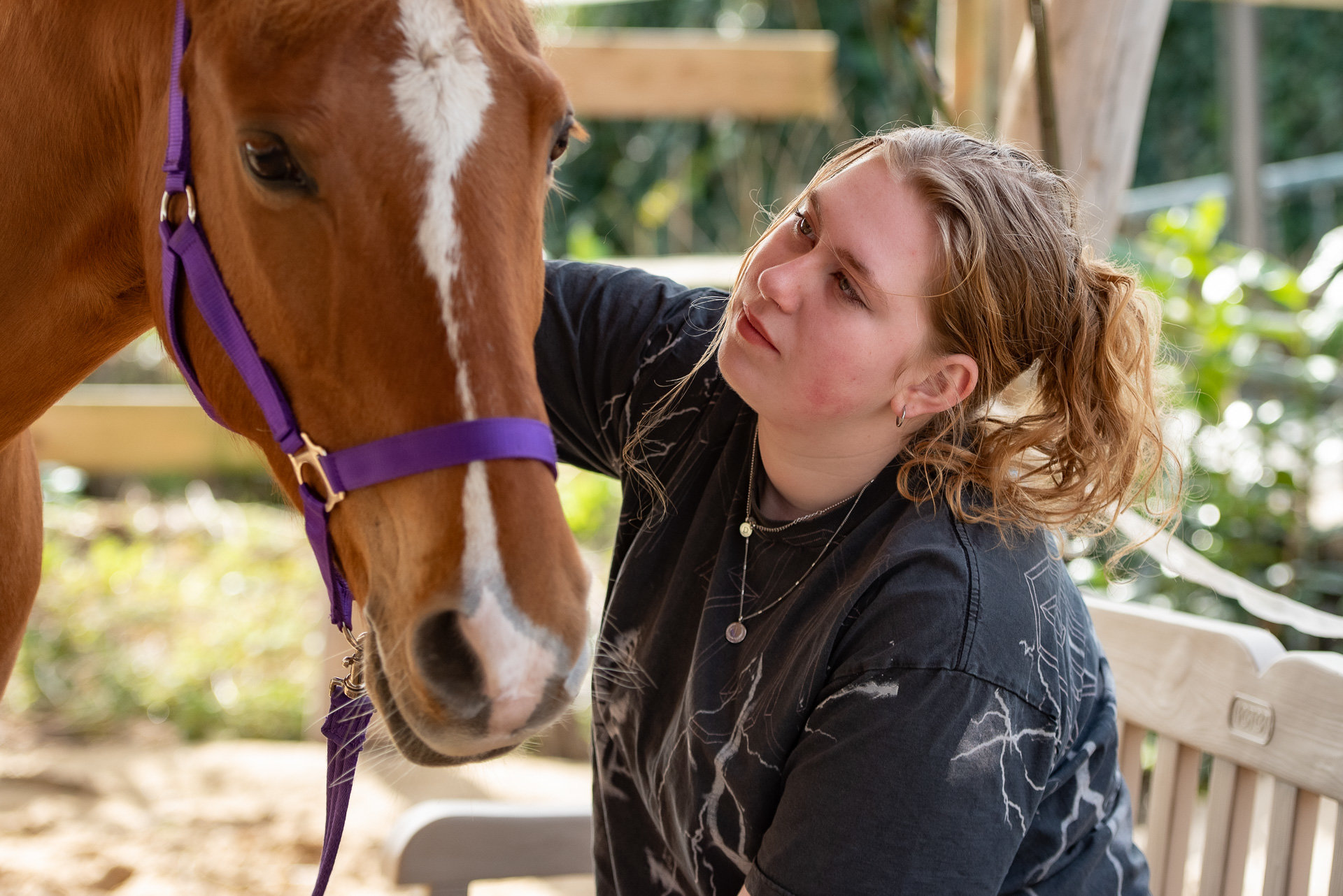 zoë zit naast de pony en kijkt deze aan terwijl de pony zich laat aanhalen