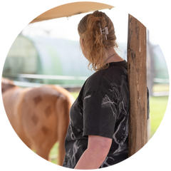 zoë staat met haar rug naar de lezer en tuurt in de verte naar een pony in de paddock