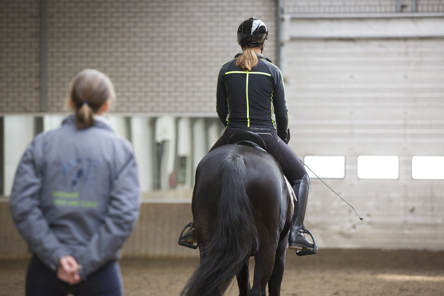 roos bekijkt de zit van sanne op het paard van achteren