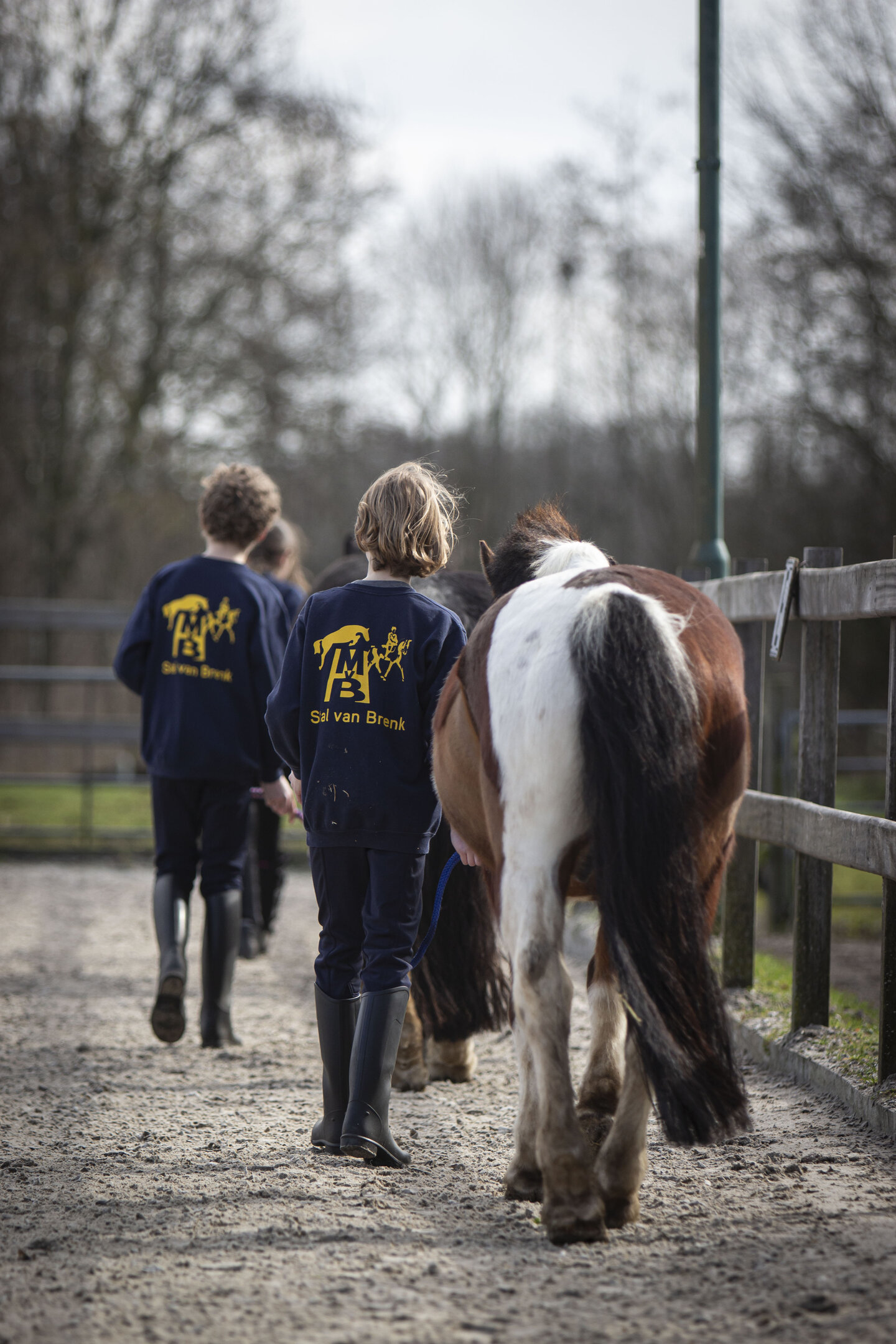 kinderen wandelen naast de pony in de buitenbak