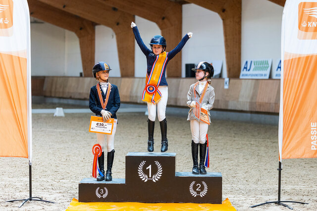 dinja van liere juicht terwijl ze op hermes zit, na het winnen van de nederlandse titel