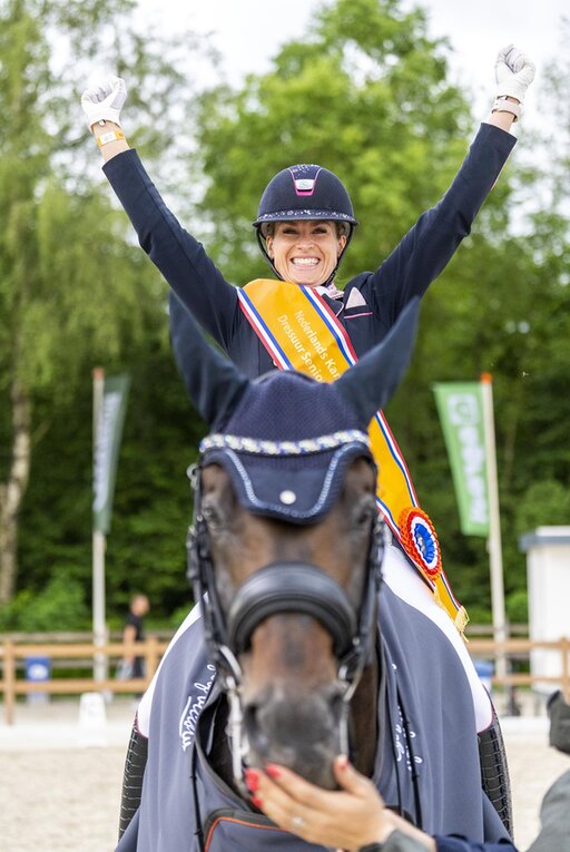 dinja van liere juicht terwijl ze op hermes zit, na het winnen van de nederlandse titel