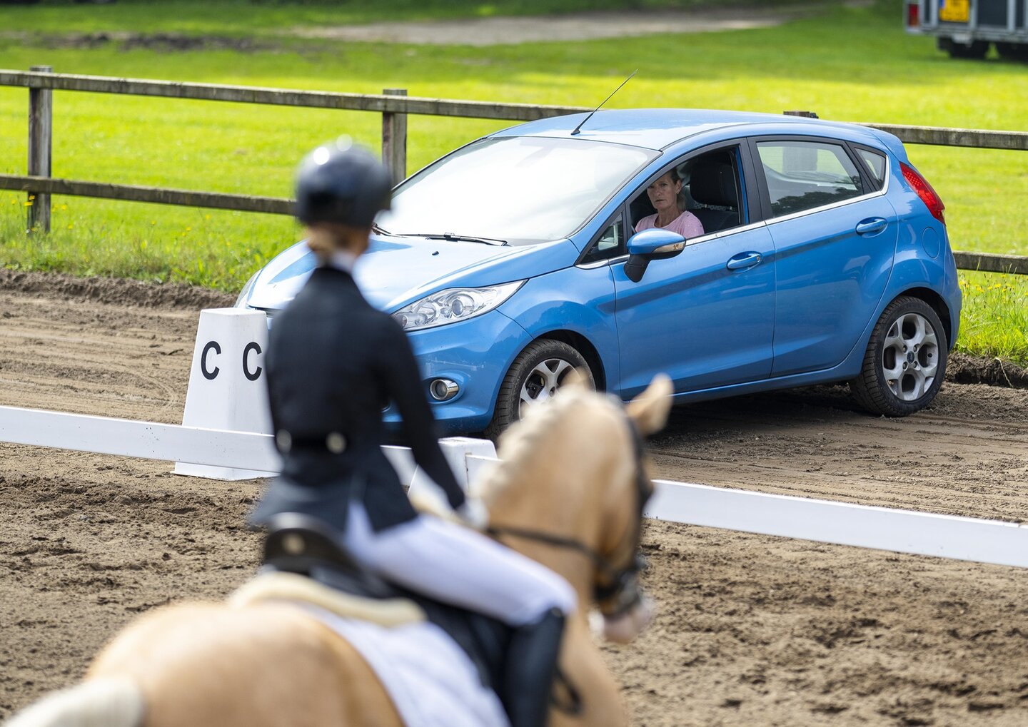 een jury kijkt vanuit de auto bij de letter c naar een dressuurcombinatie in de ring