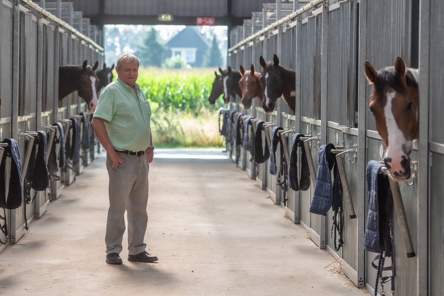 gerrit poseert in de stalgang met paarden