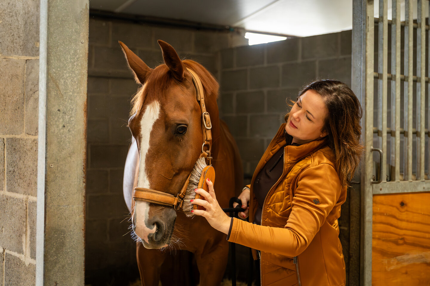 manegehouder sandra melten loopt naast een aantal ruiters met hun paard
